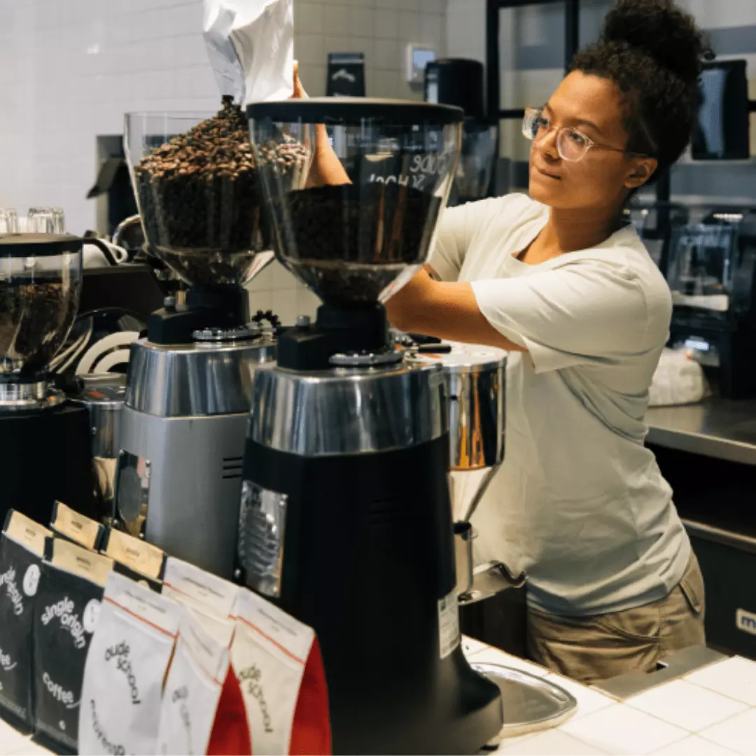 Barista Coffeecompany vult bonen bij